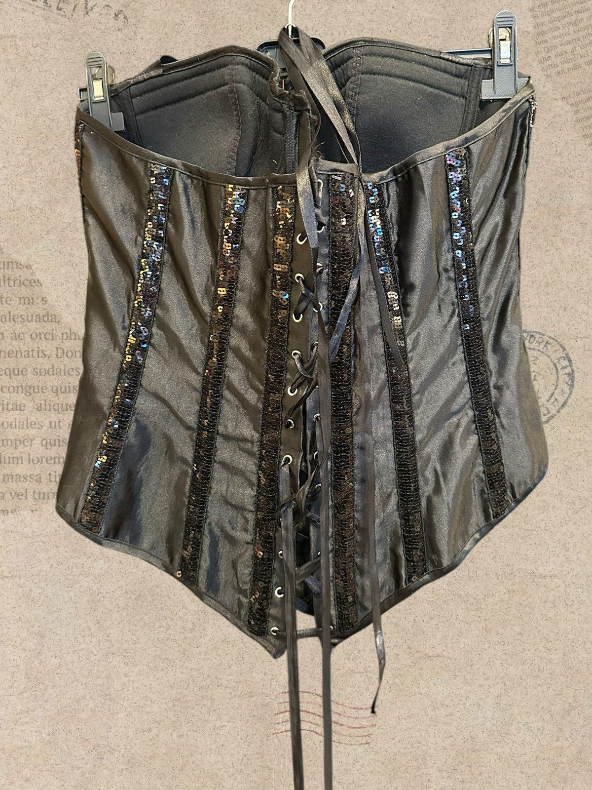 Black satin corset with sparkling sequin details. Features padded cups and adjustable lace-up back. A glamorous statement piece with gothic elegance.