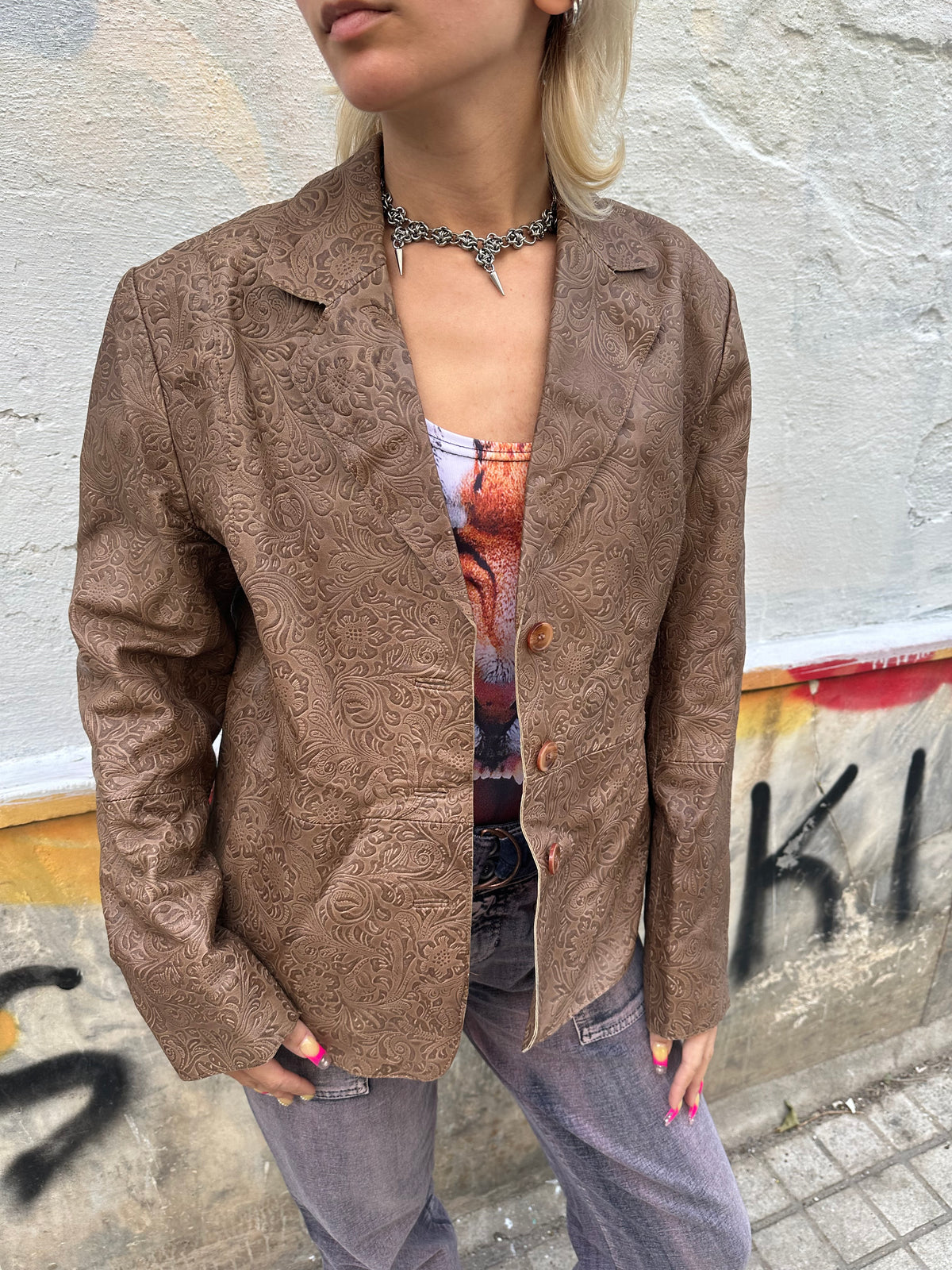 Vintage brown leather blazer with an intricate embossed floral pattern and classic button front.
A unique statement piece with tailored lines and rich textured detailing.