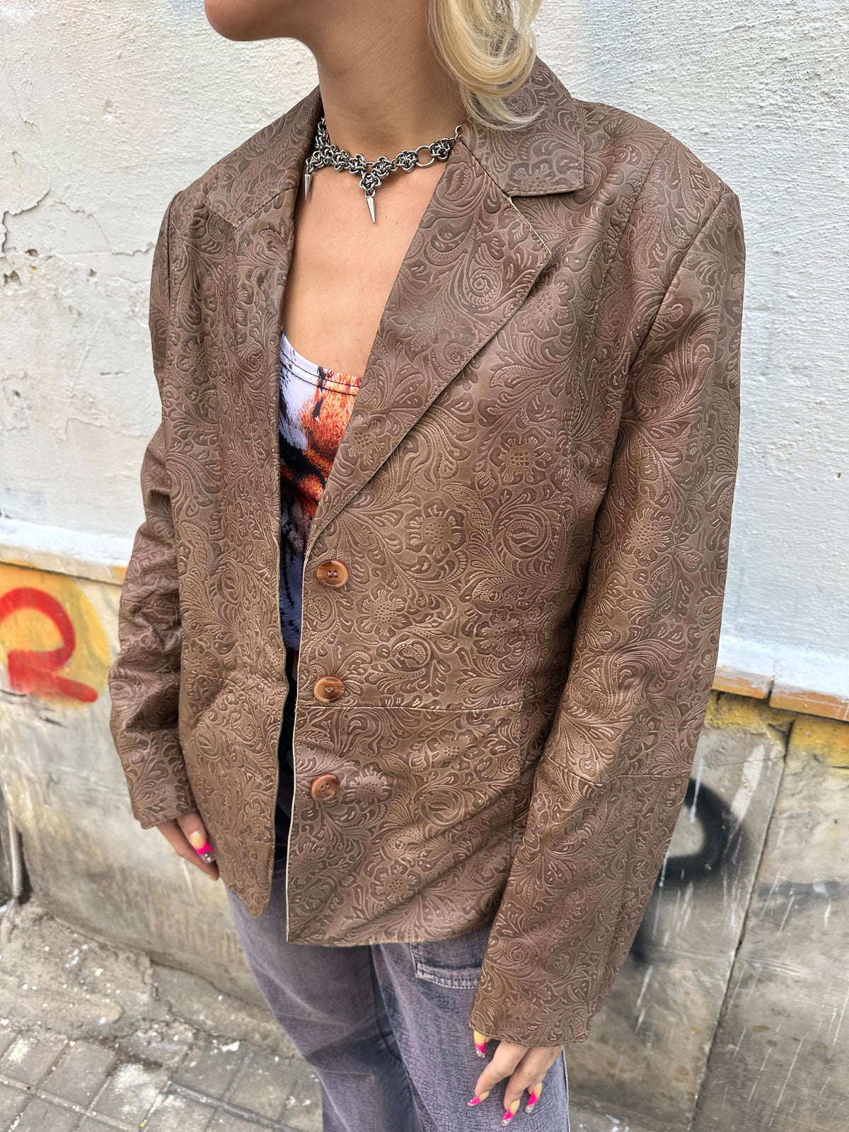 Vintage brown leather blazer with an intricate embossed floral pattern and classic button front.
A unique statement piece with tailored lines and rich textured detailing.