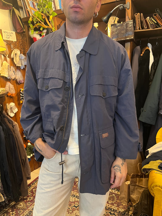 Vintage navy field jacket with a relaxed oversized fit, classic collar, and multiple flap utility pockets for a timeless military-inspired look. Features a zip-and-button front closure, adjustable details, and a warm brown wool-blend lining .