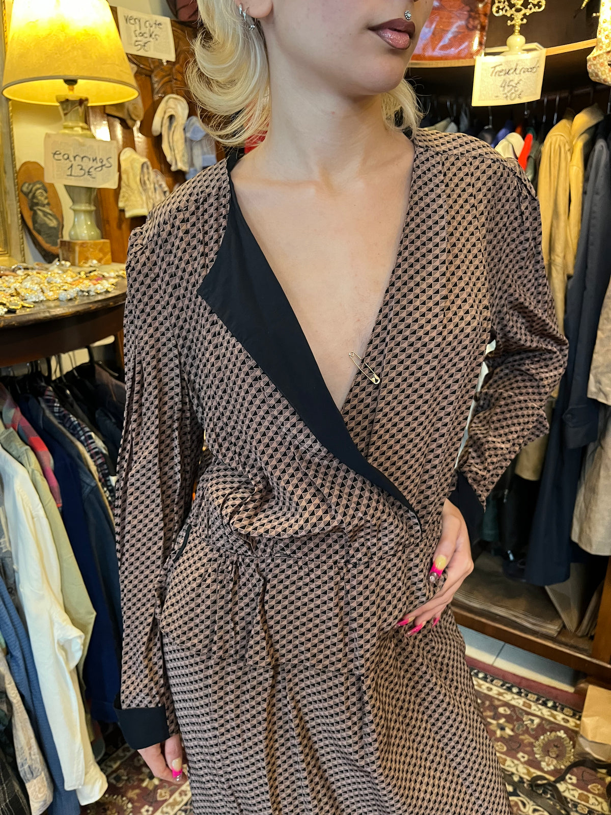 A sophisticated wrap-style midi dress featuring a geometric print, contrasting black lapels, and a flattering tie waist. Its fluid silhouette and deep V-neckline create an effortlessly elegant, timeless look