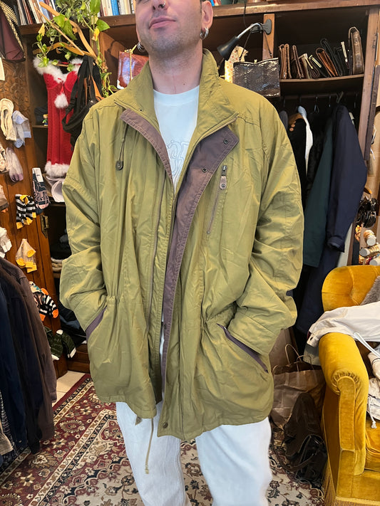 Vintage olive-green lightweight parka with contrasting brown trim, a high stand collar, and an adjustable drawstring waist for a relaxed silhouette. Finished with multiple zip and flap pockets, snap-button closure.