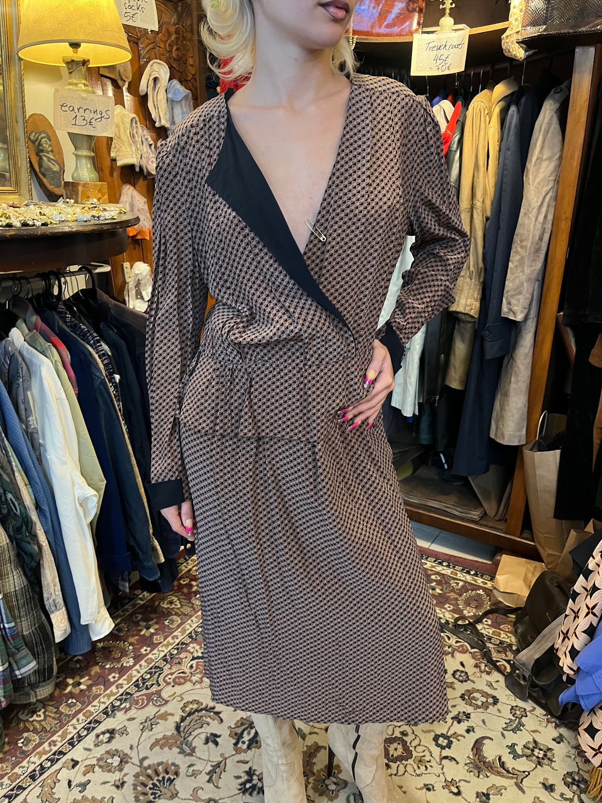 A sophisticated wrap-style midi dress featuring a geometric print, contrasting black lapels, and a flattering tie waist. Its fluid silhouette and deep V-neckline create an effortlessly elegant, timeless look