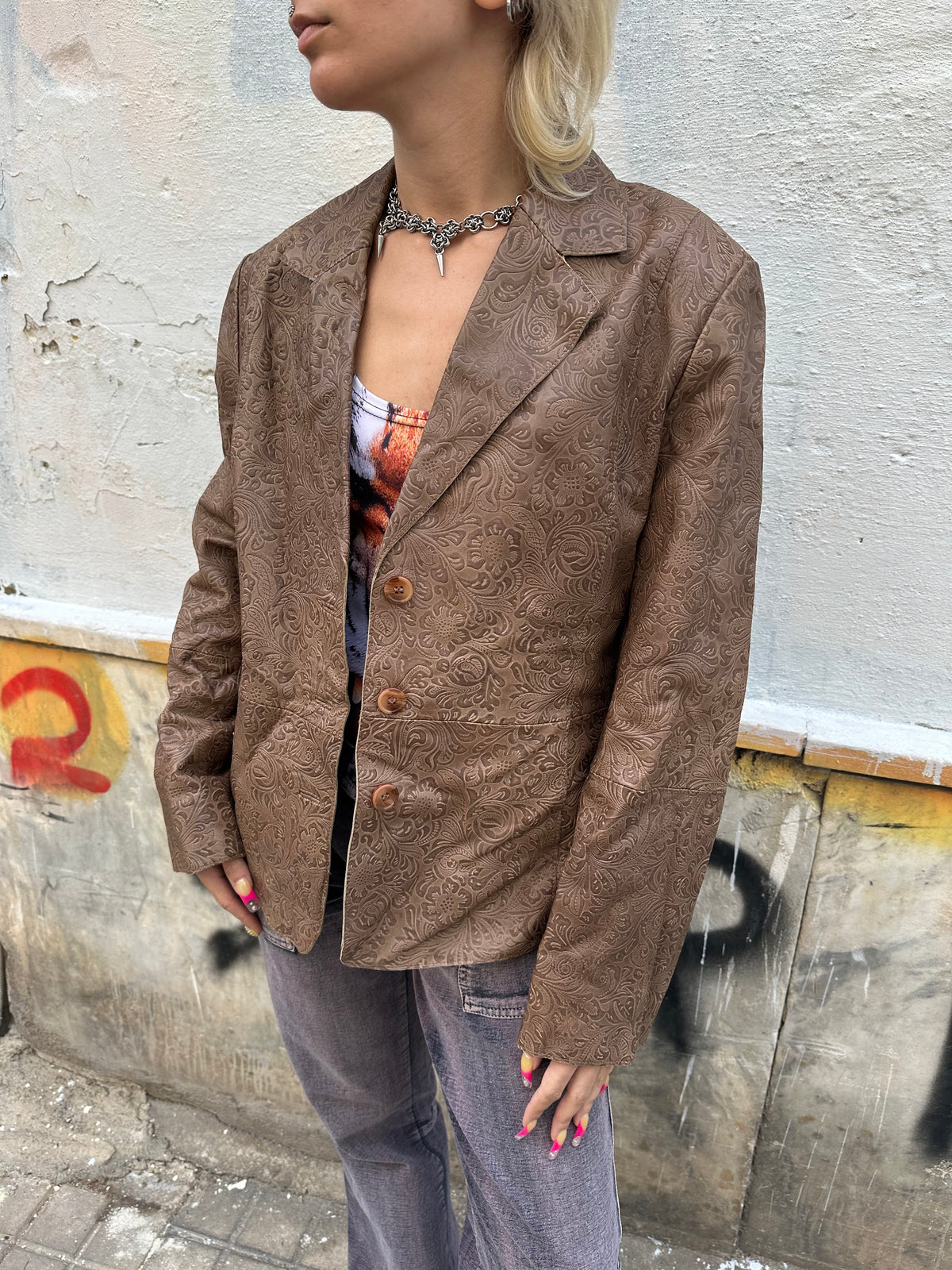 Vintage brown leather blazer with an intricate embossed floral pattern and classic button front.
A unique statement piece with tailored lines and rich textured detailing.