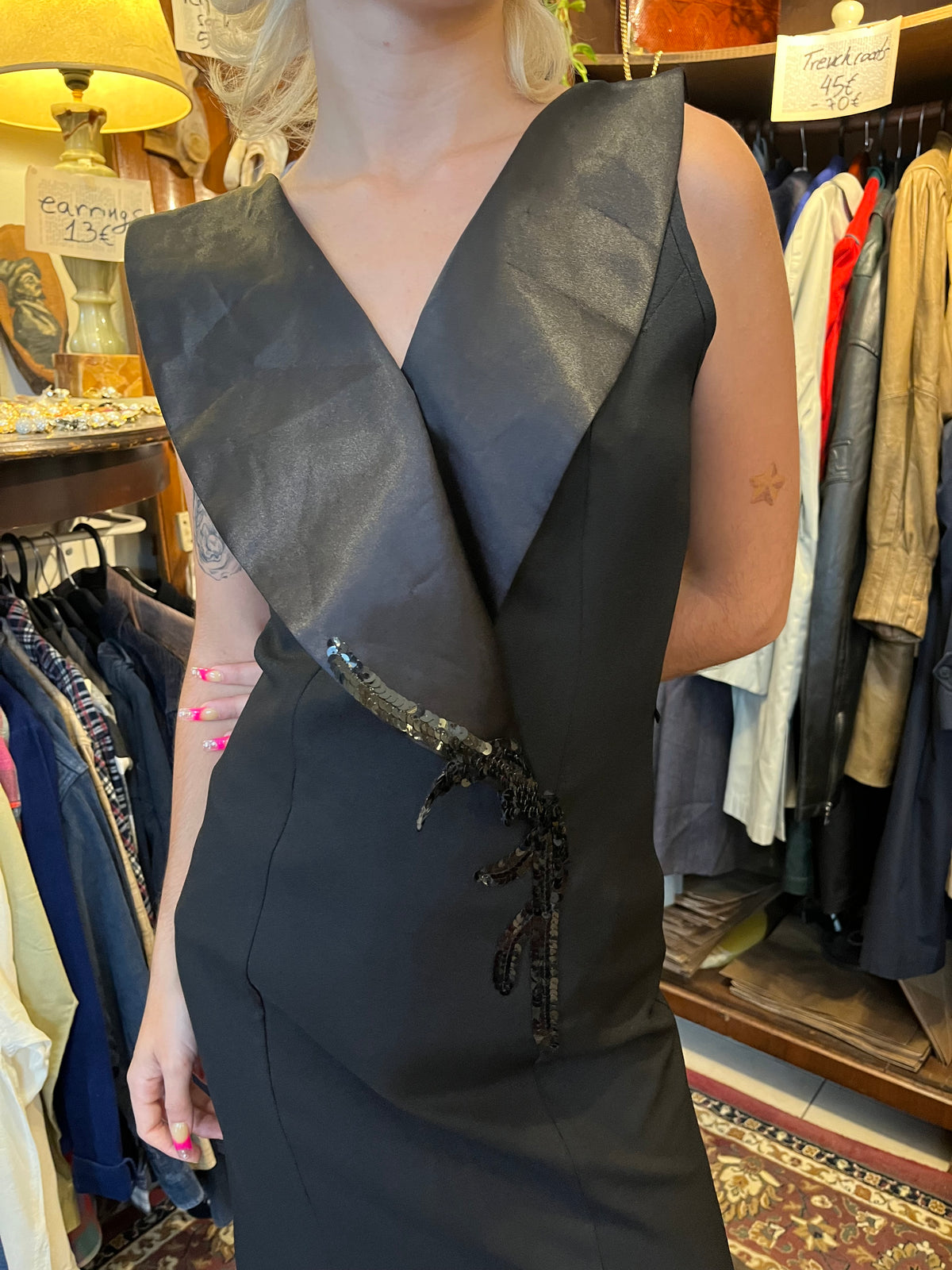 Elegant black maxi dress with a dramatic oversized V-neck collar and a sleek fitted silhouette. Finished with sequin detailing at the waist and bold front slits for a sophisticated statement look.
