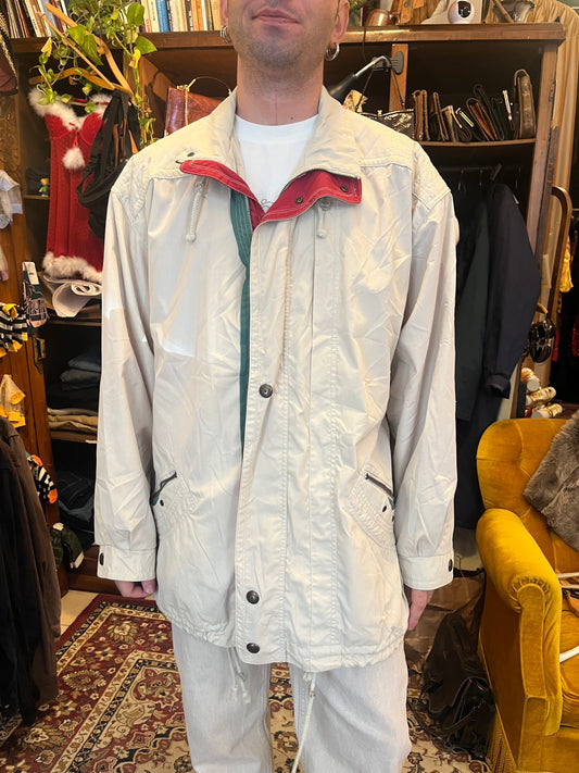 Vintage lightweight parka in off-white, featuring bold red and forest-green contrast panels along the front opening. Designed with an oversized relaxed fit, high collar, drawstring details, zip pockets.