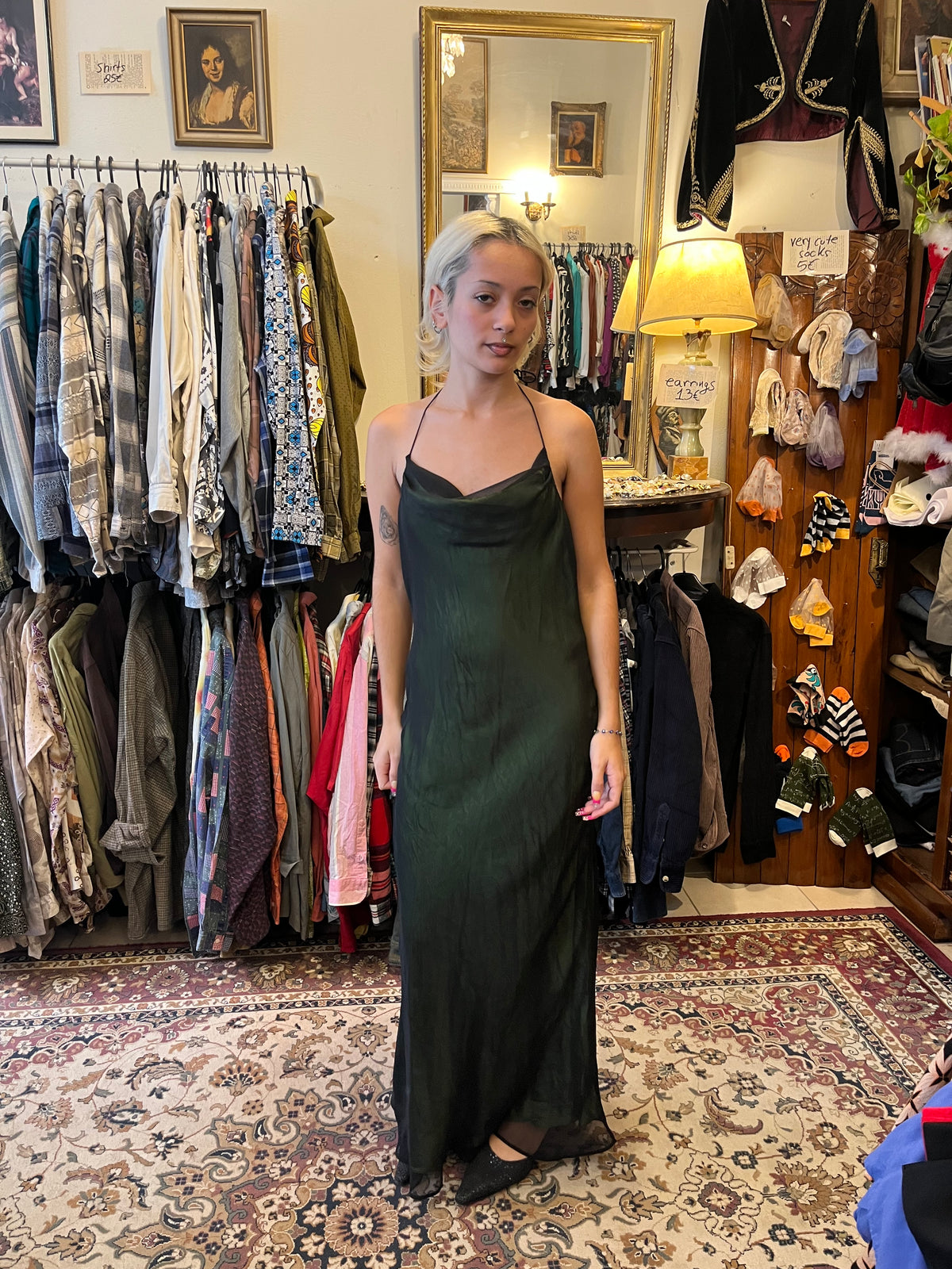 Elegant dark green maxi slip dress with a soft cowl neckline and delicate halter straps. Its fluid, semi-sheer silhouette creates an effortlessly feminine and sophisticated look.