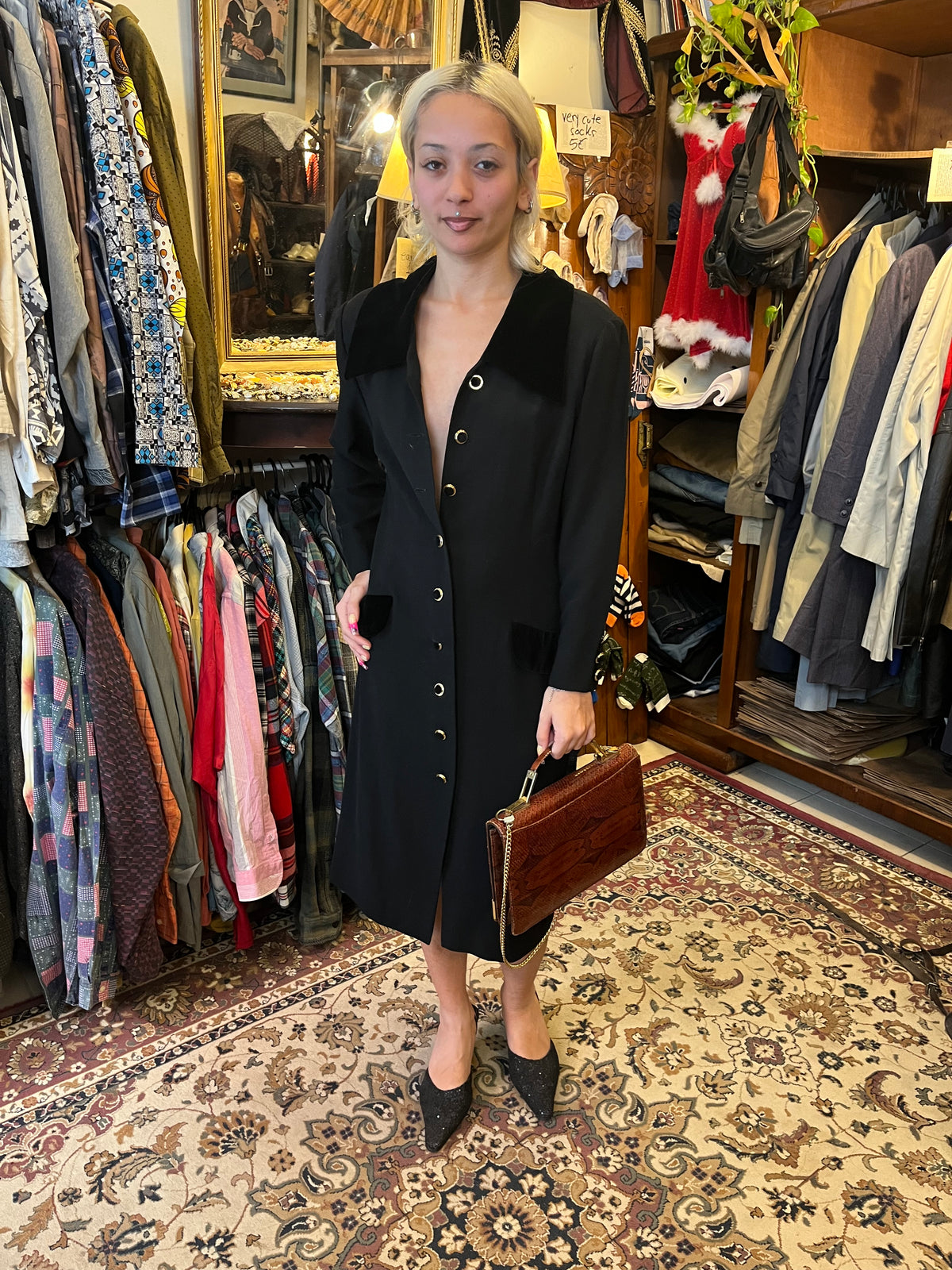 Elegant vintage black midi coat dress featuring a statement velvet collar and gold-tone buttons. Tailored silhouette with velvet pocket details for a timeless, sophisticated look.