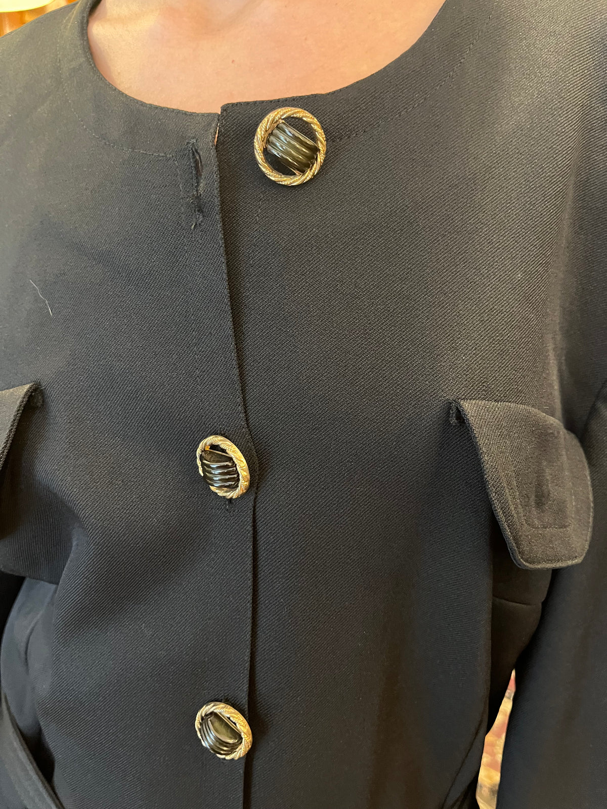 Vintage black midi coat dress featuring statement gold-tone buttons, multiple flap pockets and a matching waist belt. A structured, timeless silhouette with an elegant military-inspired feel.