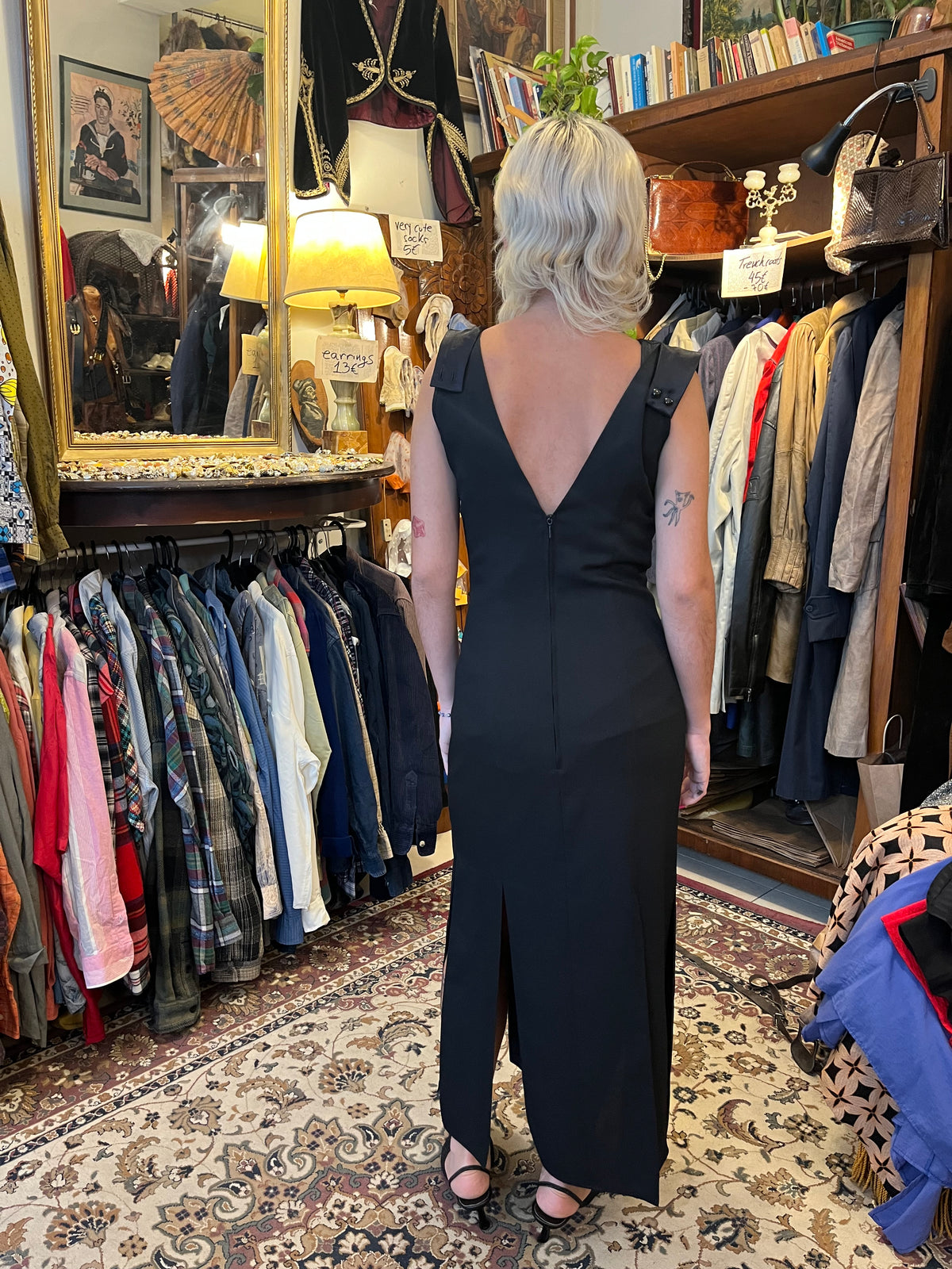 Elegant black maxi dress with a dramatic oversized V-neck collar and a sleek fitted silhouette. Finished with sequin detailing at the waist and bold front slits for a sophisticated statement look.