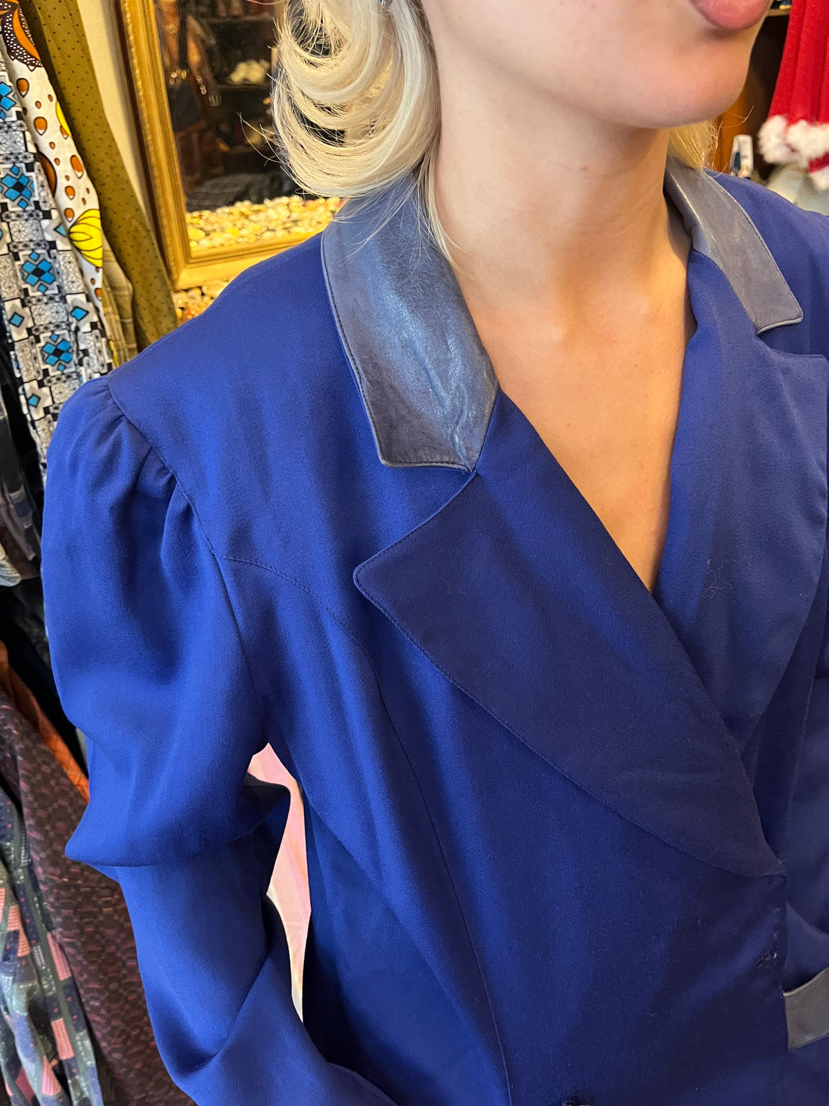 Vintage royal blue midi dress with a structured blazer-style silhouette and elegant puffed shoulders. Contrasting satin-effect collar and pocket details add a sophisticated retro touch.