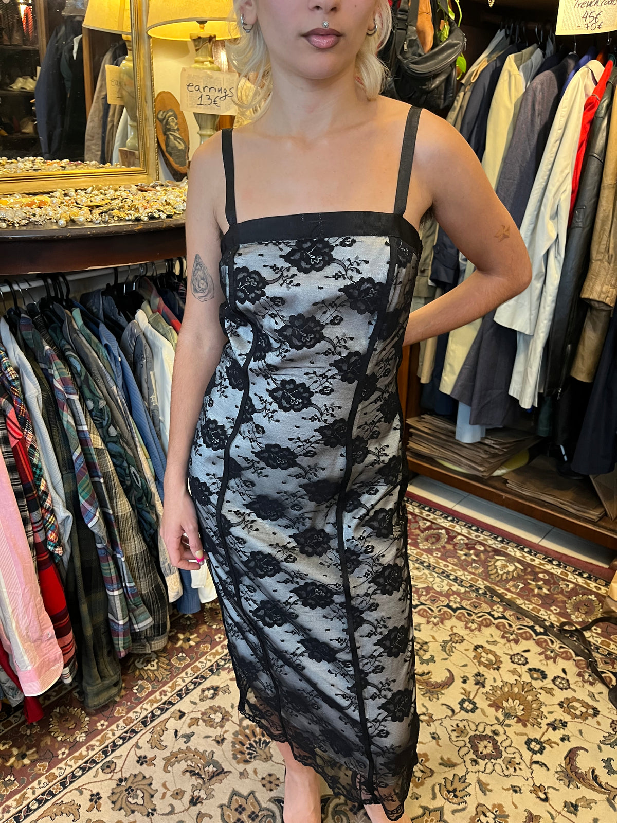Elegant black lace midi dress with a contrasting silver lining, delicate floral detailing and slim straps. The fitted silhouette creates a timeless, feminine look with a romantic vintage feel