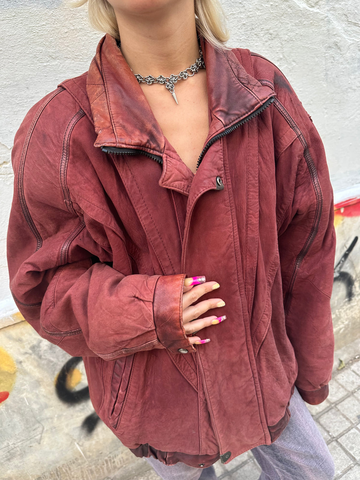 Vintage burgundy leather bomber jacket with an oversized fit and distressed finish.
Statement panel detailing, zip closure, and an authentic 80s/90s biker aesthetic.