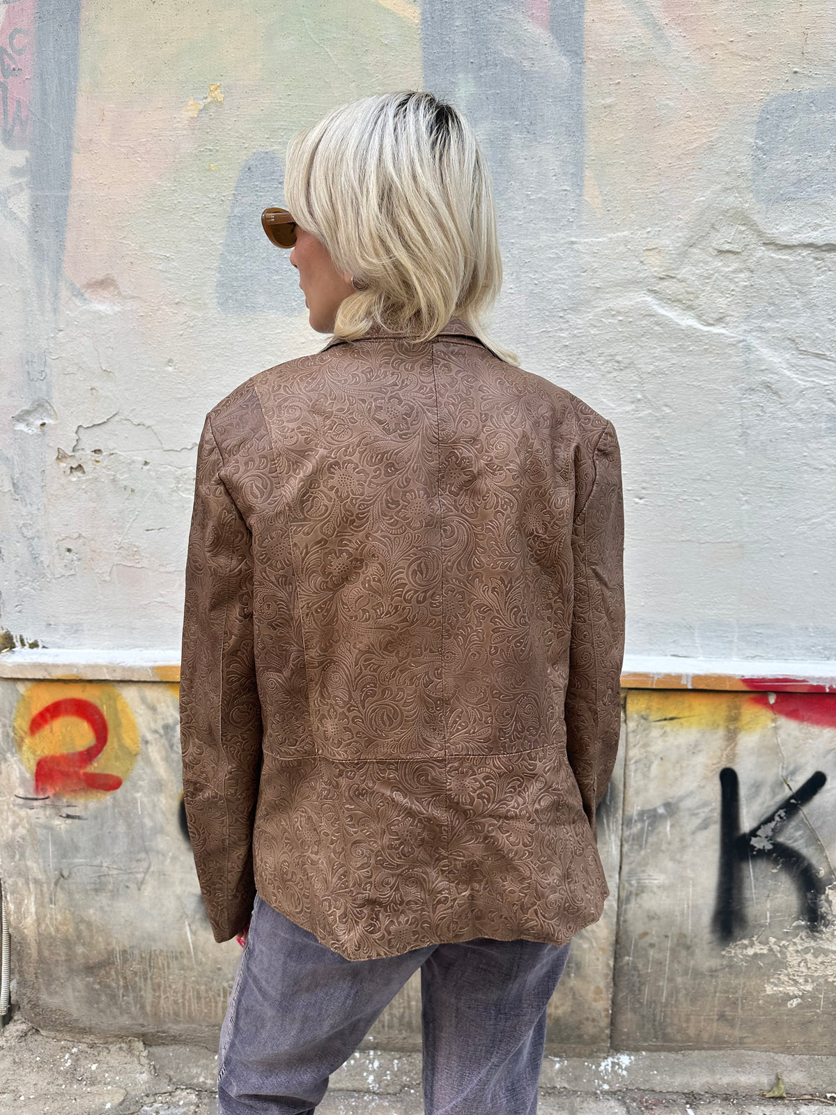 Vintage brown leather blazer with an intricate embossed floral pattern and classic button front.
A unique statement piece with tailored lines and rich textured detailing.