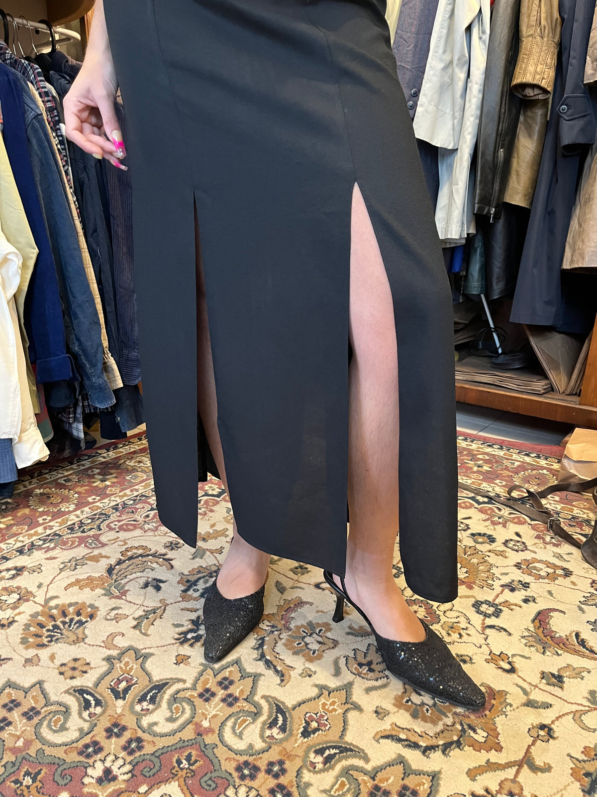 Elegant black maxi dress with a dramatic oversized V-neck collar and a sleek fitted silhouette. Finished with sequin detailing at the waist and bold front slits for a sophisticated statement look.