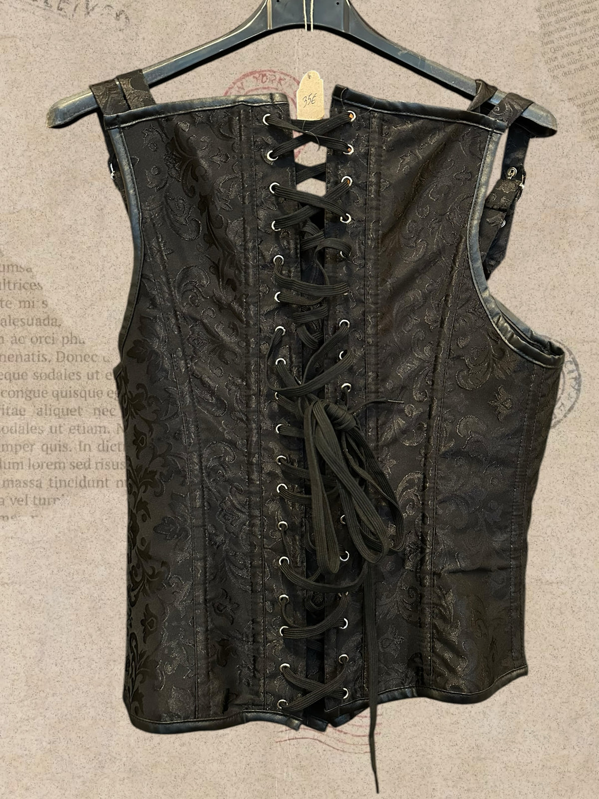 Black brocade corset with elegant floral patterns. Silver clasps, buckle straps and adjustable lace-up back. A bold gothic Victorian statement piece.