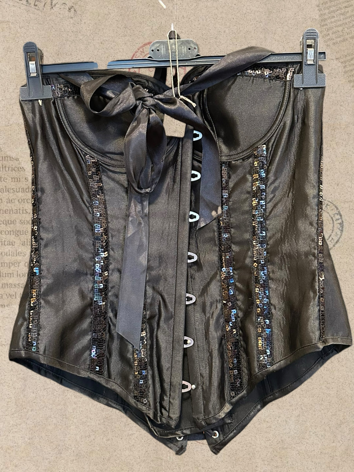 Black satin corset with sparkling sequin details. Features padded cups and adjustable lace-up back. A glamorous statement piece with gothic elegance.