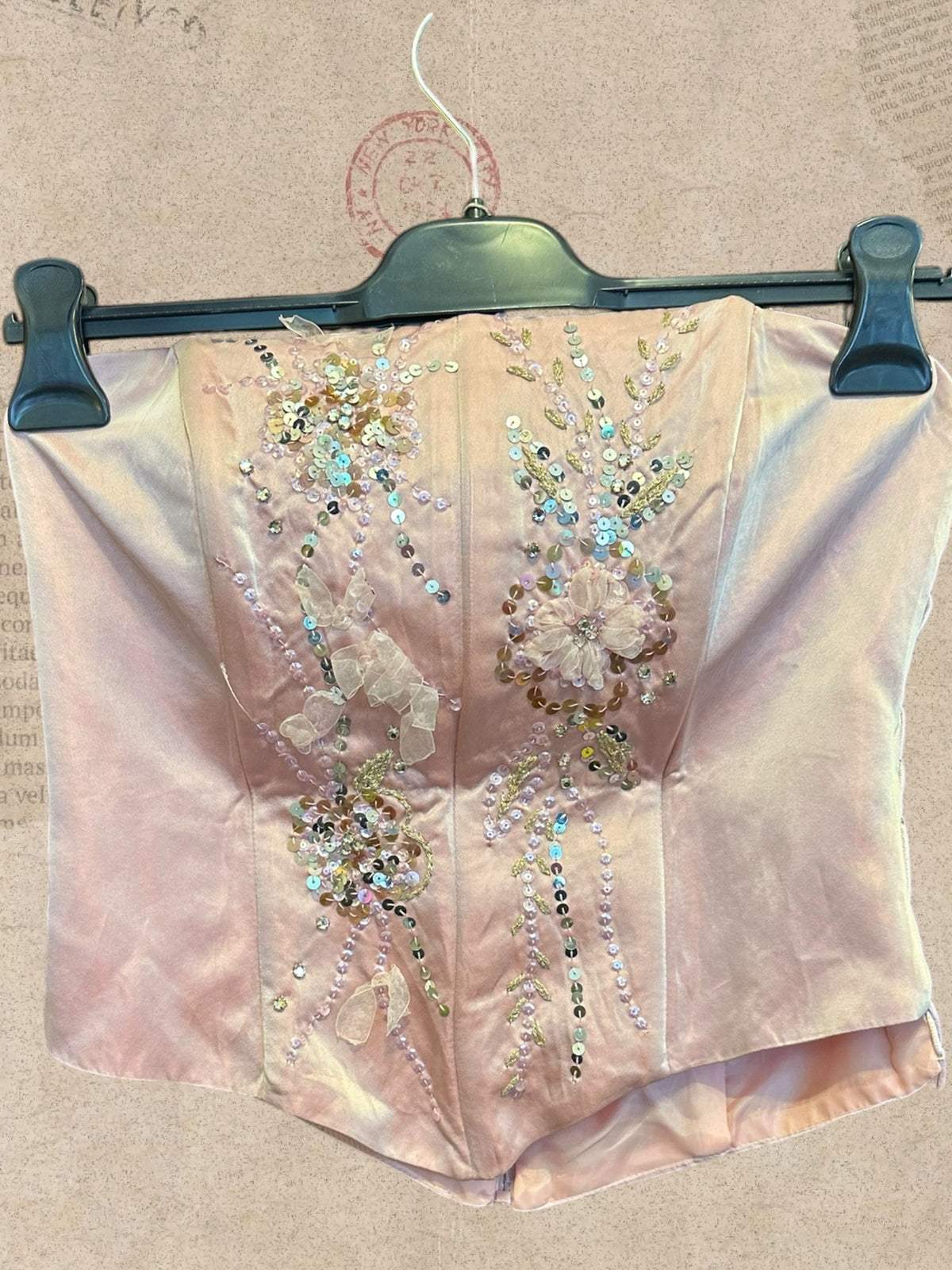 Blush pink satin corset with sparkling sequins and floral details. Side lace-up ties and back zipper. Romantic, elegant style.