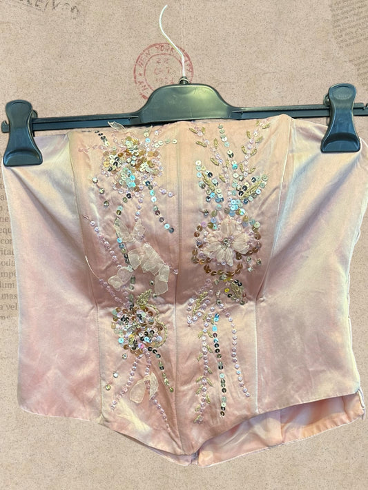 Blush pink satin corset with sparkling sequins and floral details. Side lace-up ties and back zipper. Romantic, elegant style.