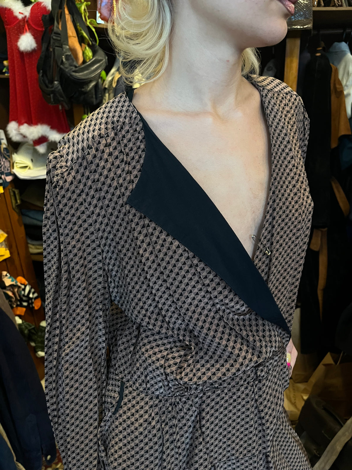 A sophisticated wrap-style midi dress featuring a geometric print, contrasting black lapels, and a flattering tie waist. Its fluid silhouette and deep V-neckline create an effortlessly elegant, timeless look