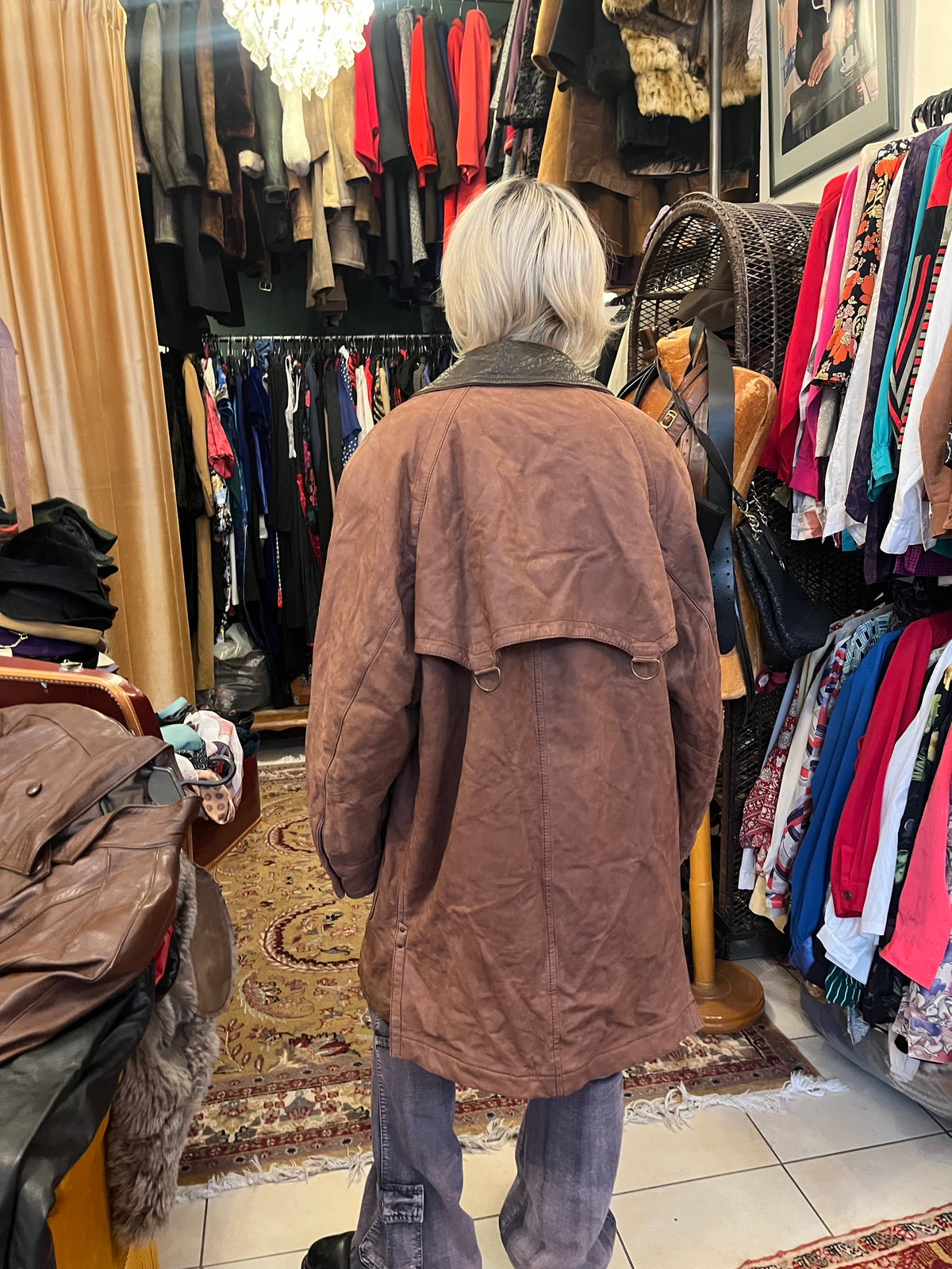 Vintage brown leather coat featuring a contrasting dark leather collar and utility-inspired patch pockets. Designed with a relaxed longline silhouette, button-front closure, and distinctive cape-style back panel
