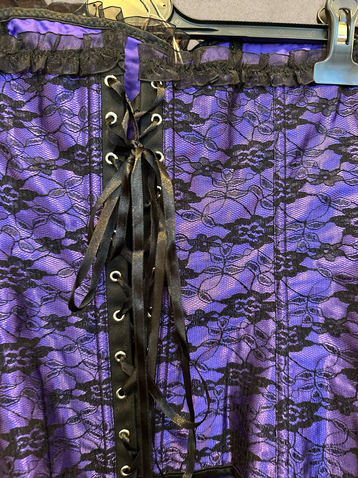 Gothic purple satin corset with black floral lace and ruffled trims. Adjustable lace-up design for a perfect fit. A romantic statement piece with Victorian charm.
