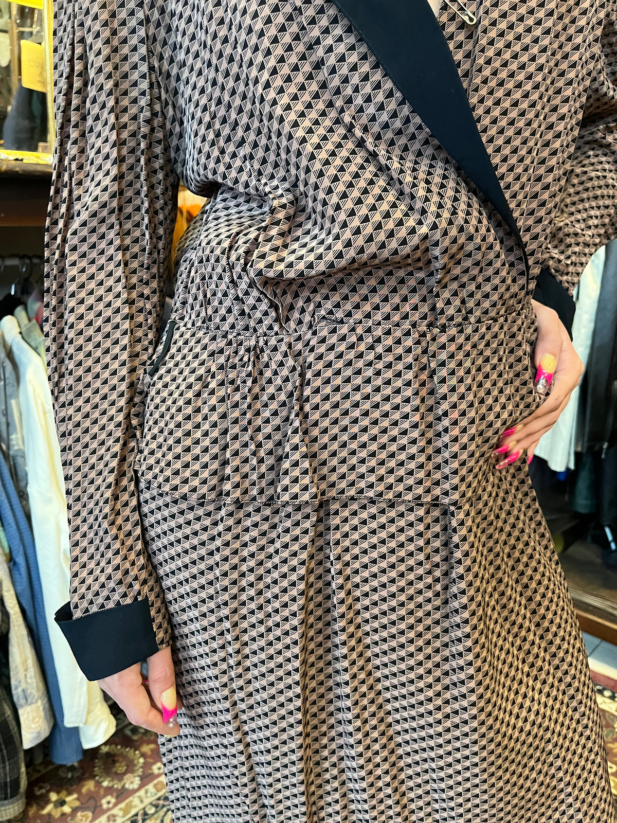 A sophisticated wrap-style midi dress featuring a geometric print, contrasting black lapels, and a flattering tie waist. Its fluid silhouette and deep V-neckline create an effortlessly elegant, timeless look