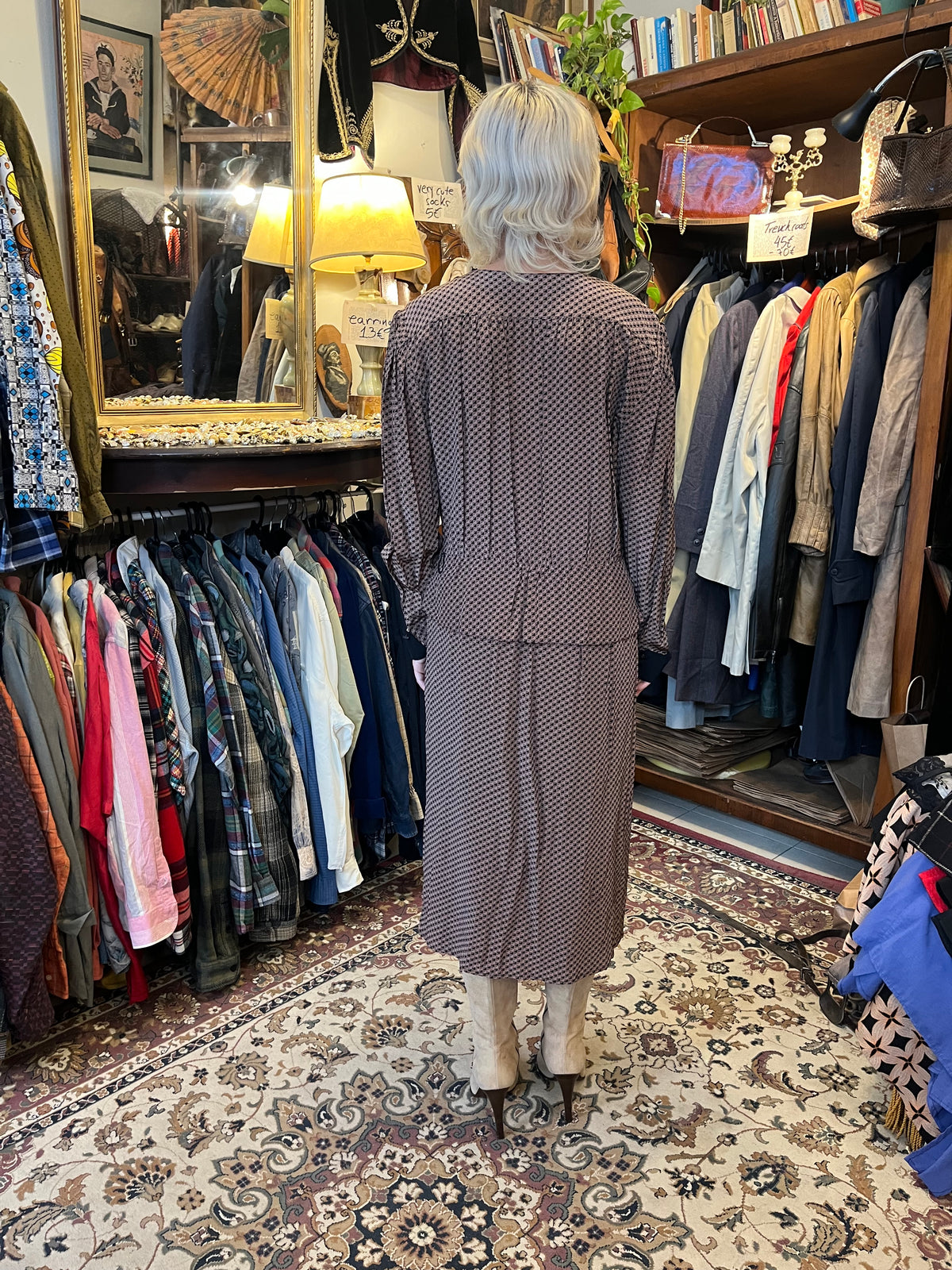 A sophisticated wrap-style midi dress featuring a geometric print, contrasting black lapels, and a flattering tie waist. Its fluid silhouette and deep V-neckline create an effortlessly elegant, timeless look