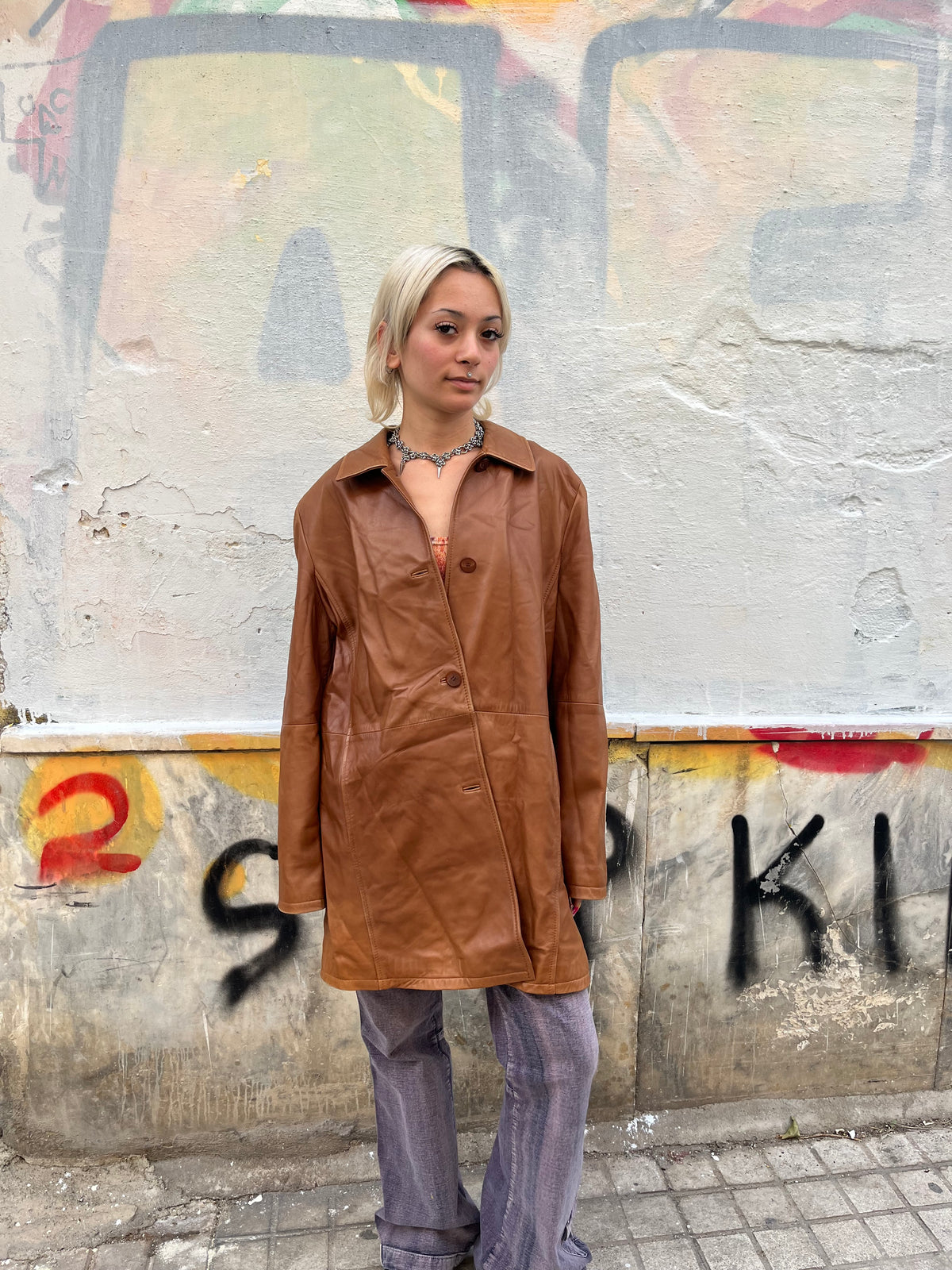 Vintage caramel-brown leather coat with a clean, minimalist silhouette and softly structured fit. Features a classic pointed collar, tonal button closure, subtle side pockets, and a beautifully aged leather finish.