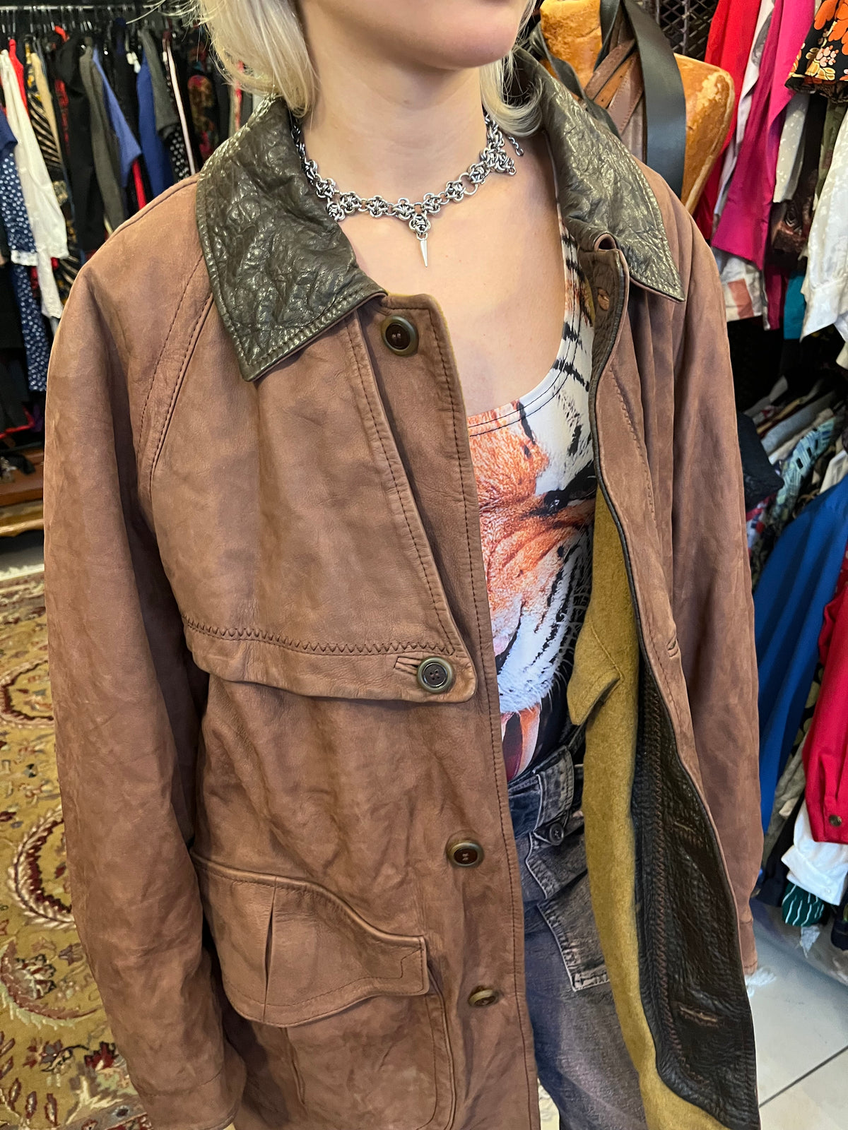 Vintage brown leather coat featuring a contrasting dark leather collar and utility-inspired patch pockets. Designed with a relaxed longline silhouette, button-front closure, and distinctive cape-style back panel