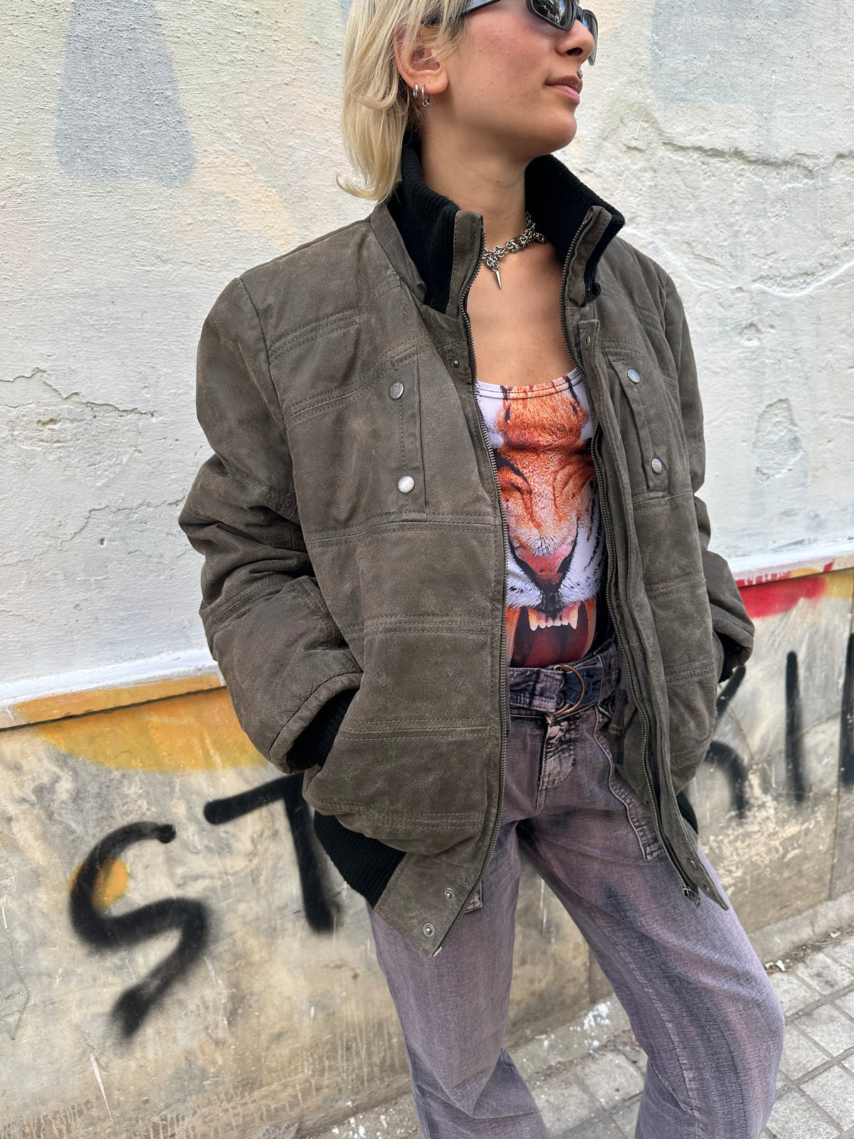 Vintage taupe suede bomber jacket with an oversized fit and distressed finish.
Black ribbed details, high collar, and a bold 80s/90s utility aesthetic.