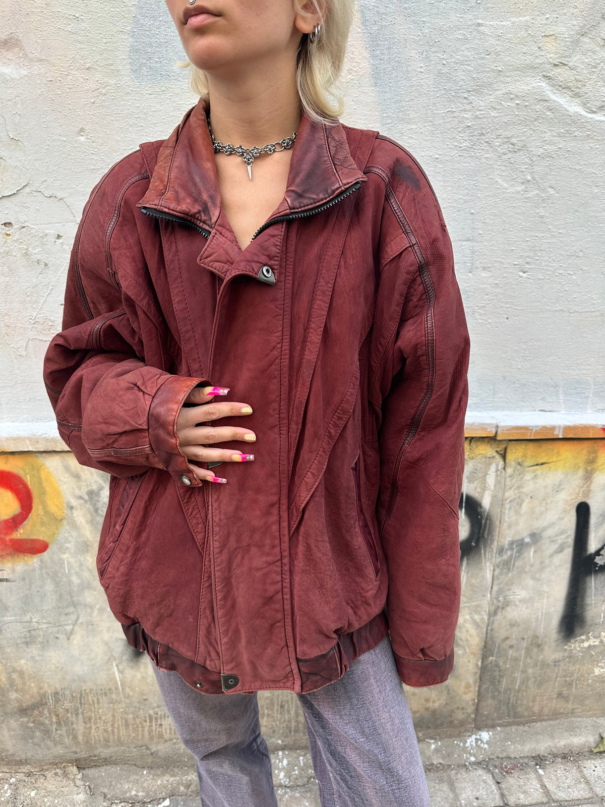 Vintage burgundy leather bomber jacket with an oversized fit and distressed finish.
Statement panel detailing, zip closure, and an authentic 80s/90s biker aesthetic.
