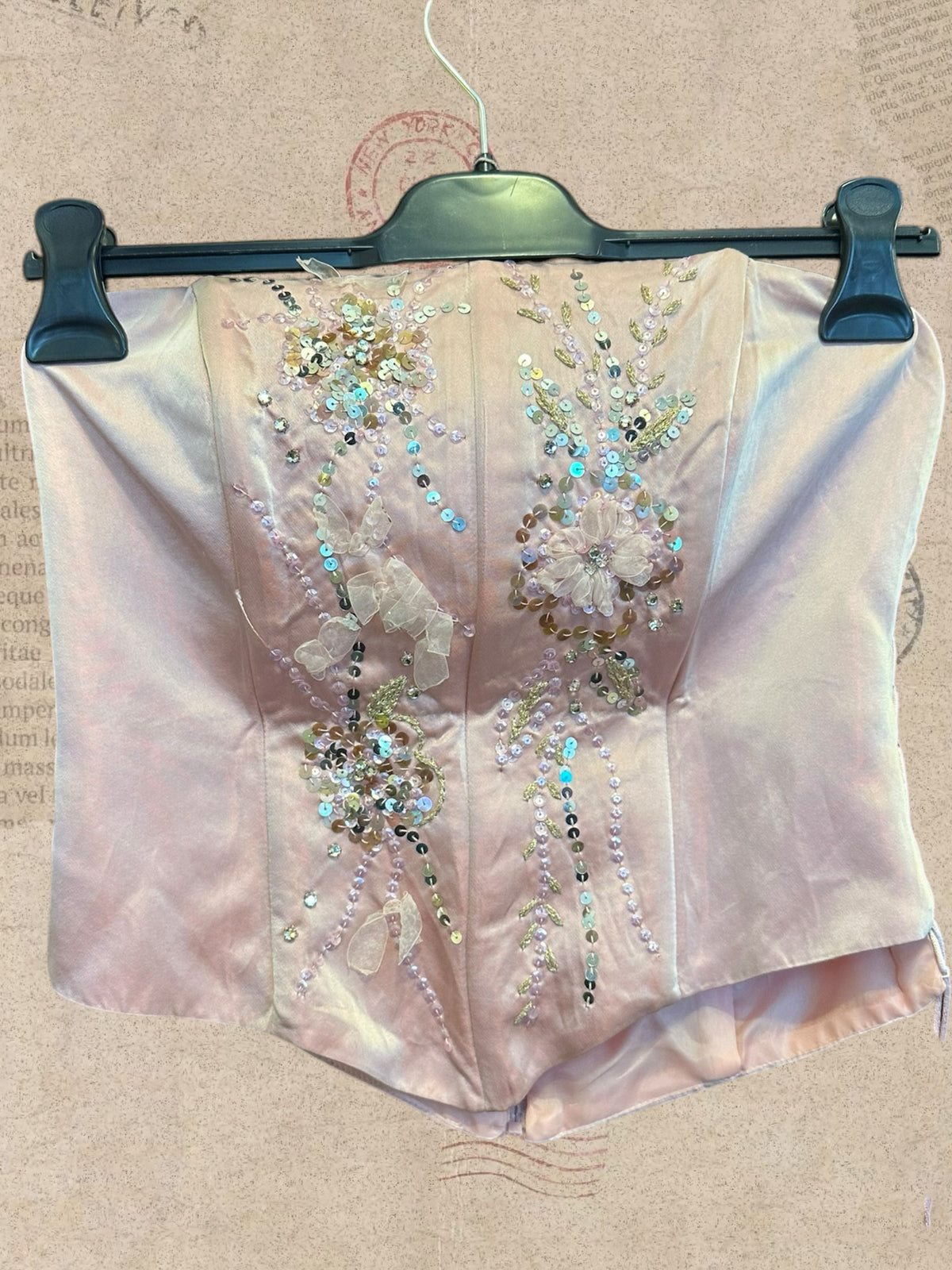 Blush pink satin corset with sparkling sequins and floral details. Side lace-up ties and back zipper. Romantic, elegant style.