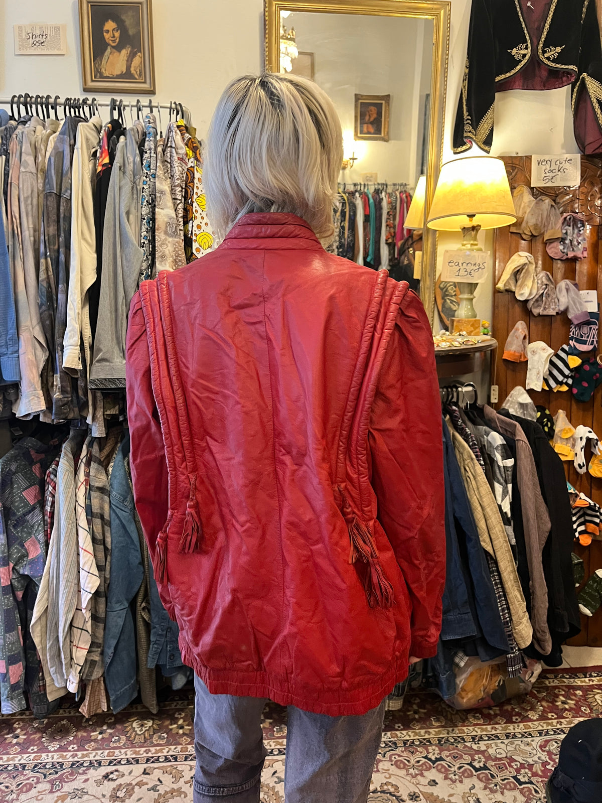 Statement red leather jacket featuring sculptural braided detailing and playful tassel accents. A bold vintage piece with a relaxed silhouette, zip-front closure, and unmistakable 80s-inspired attitude.